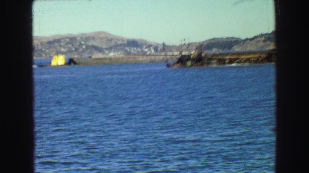 Bay water with distant shoreline and a small yellow structure near the left edge.