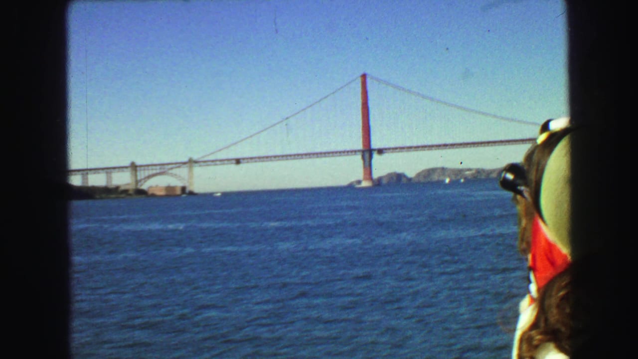 Golden Gate Bridge spans blue water with a passenger partly visible at right.