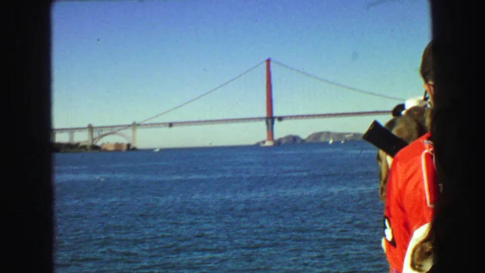 Golden Gate Bridge and bay water fill the frame while passengers stand along the right edge in this 1968 8mm home-movie view.
