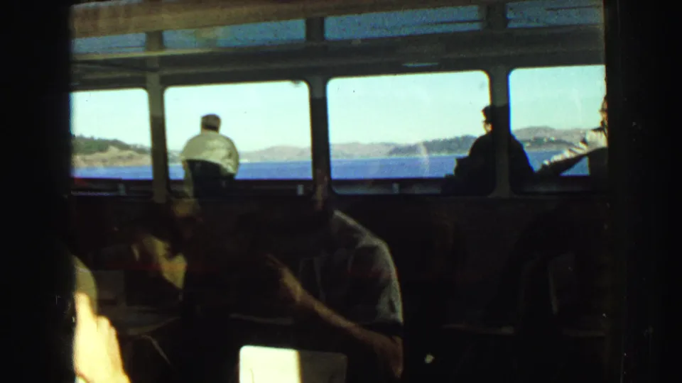 Inside a boat bridge or cabin near Vancouver in 1968, passengers appear in shadow against bright windows overlooking open water and distant shore.