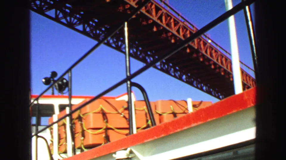 1968 Vancouver home-movie frame from the deck, with orange life rafts and red railing under a steel bridge.