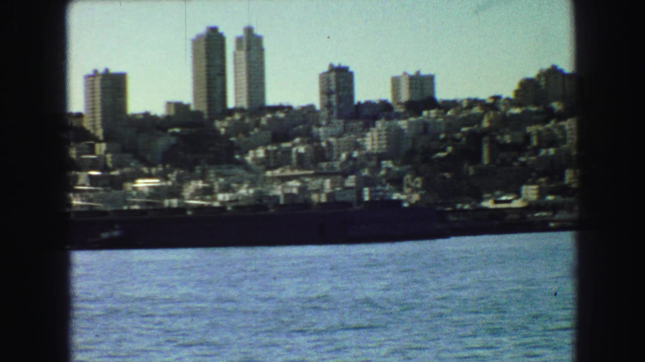 Distant city skyline with twin high-rise towers above rippling water.