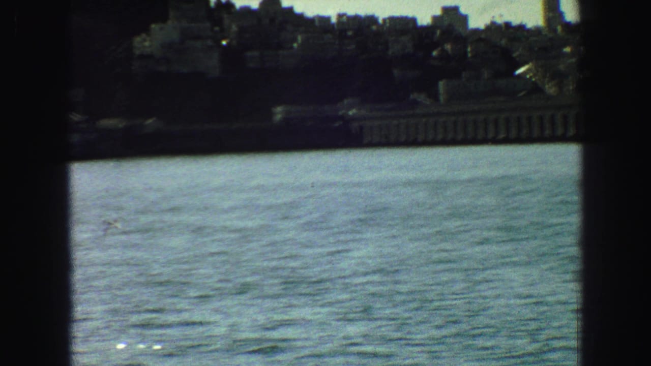 Waterfront cityscape seen across water through dark vertical framing.