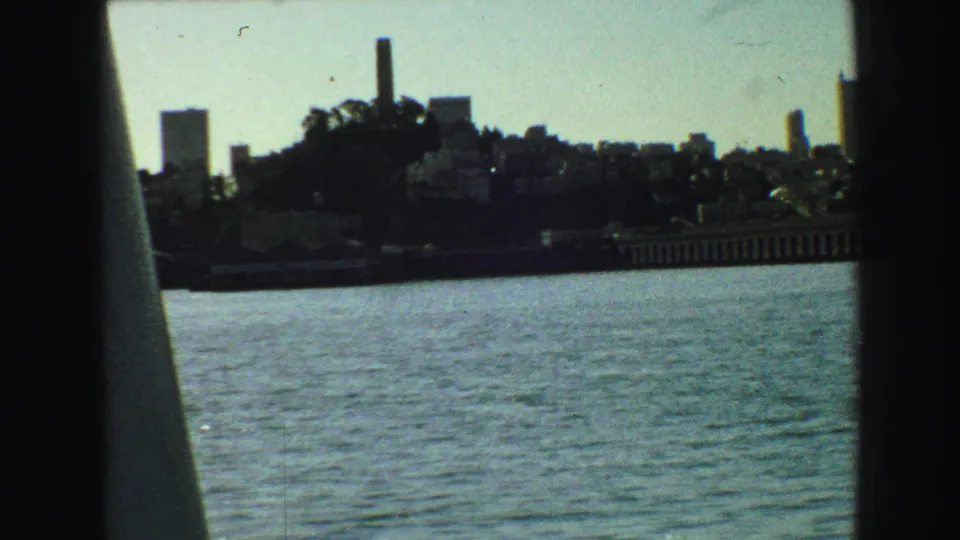 Vancouver waterfront skyline from 1968 with a hillside, tall vertical stack-like structure, distant towers, and water in the foreground.