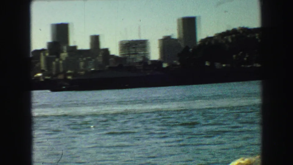 1968 Vancouver waterfront skyline with high-rises seen across blue-green water through boat framing.