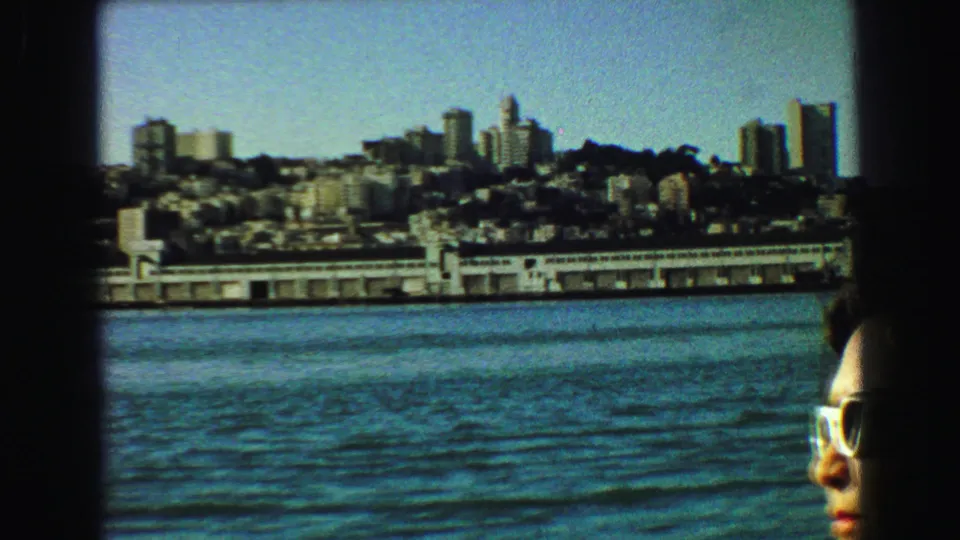 Partial adult woman in sunglasses at the edge of a 1968 Vancouver waterfront skyline view.
