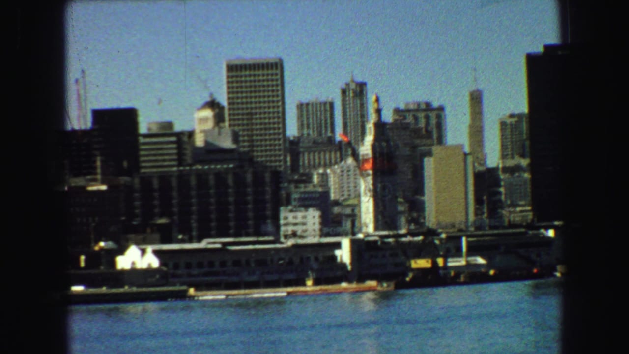 Vancouver skyline across blue harbor water with tall buildings and a distant bridge.