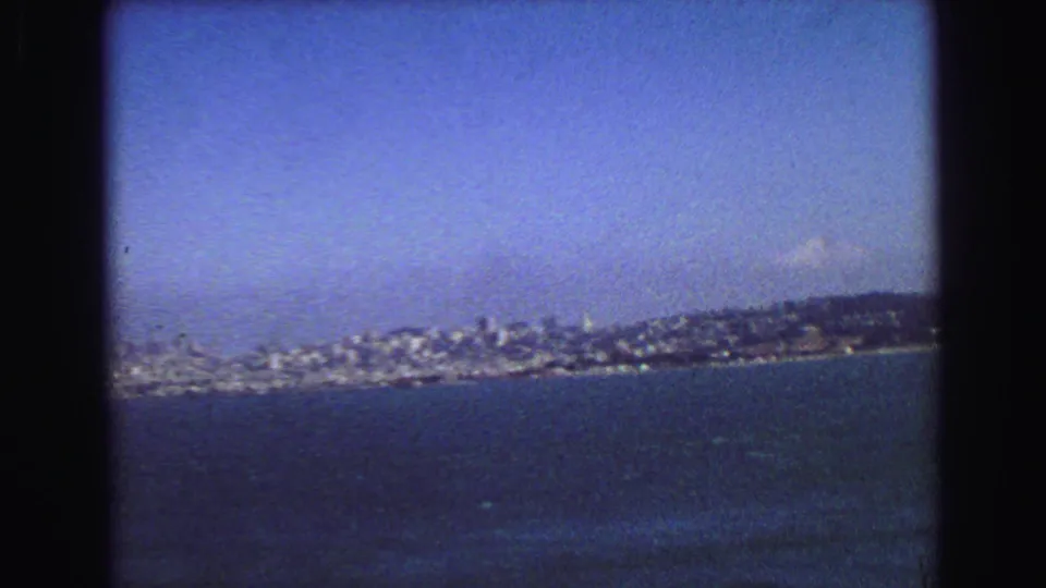 1968 8mm frame with a broad bay view toward dense shoreline buildings and low hills in the distance.