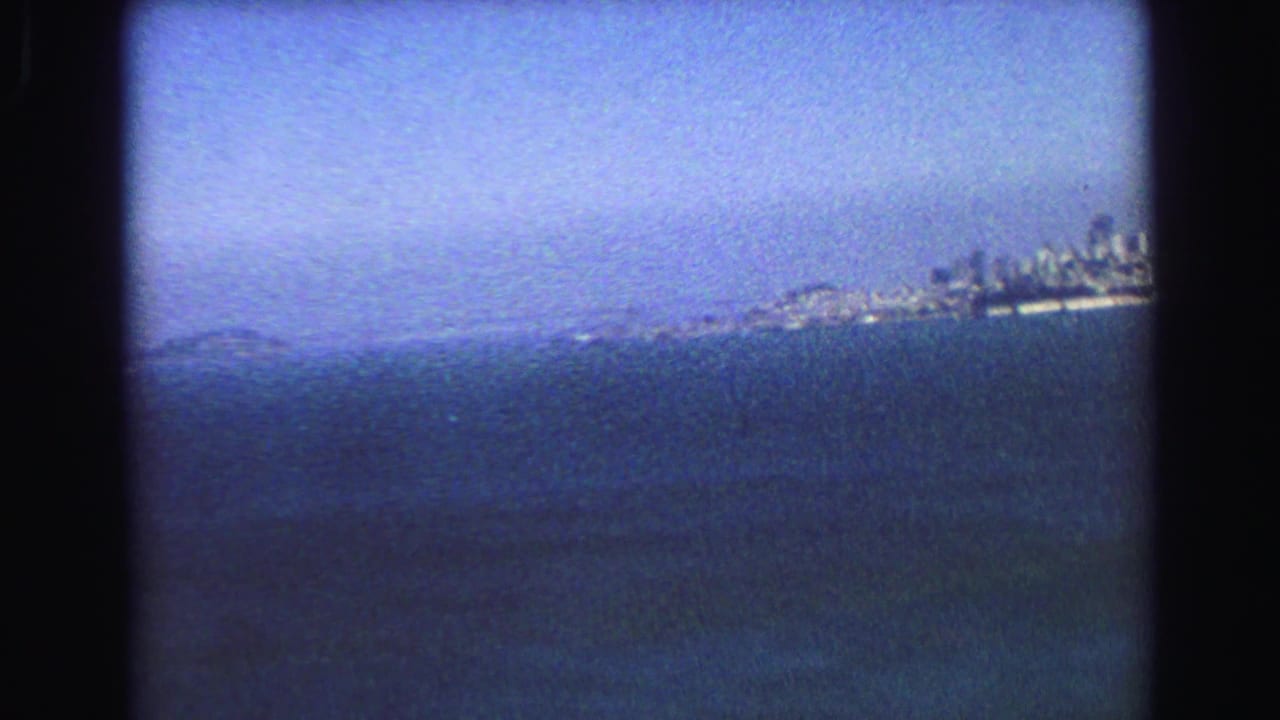 Hazy water view with distant shoreline and city-like skyline near the right edge.