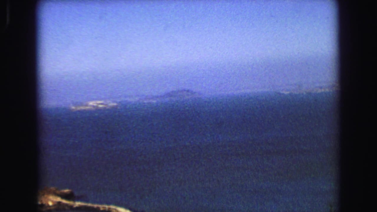 Hazy 1968 Vancouver coastal view with open water, distant land, and a bright shoreline patch across the bay.