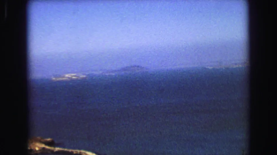 Hazy 1968 Vancouver coastal view with open water, distant land, and a bright shoreline patch across the bay.