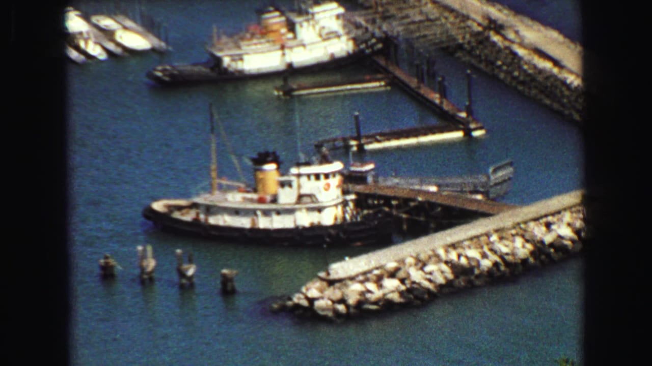 Zoomed 1968 Vancouver harbor detail showing a tug-like vessel docked beside piers and a rocky breakwater.