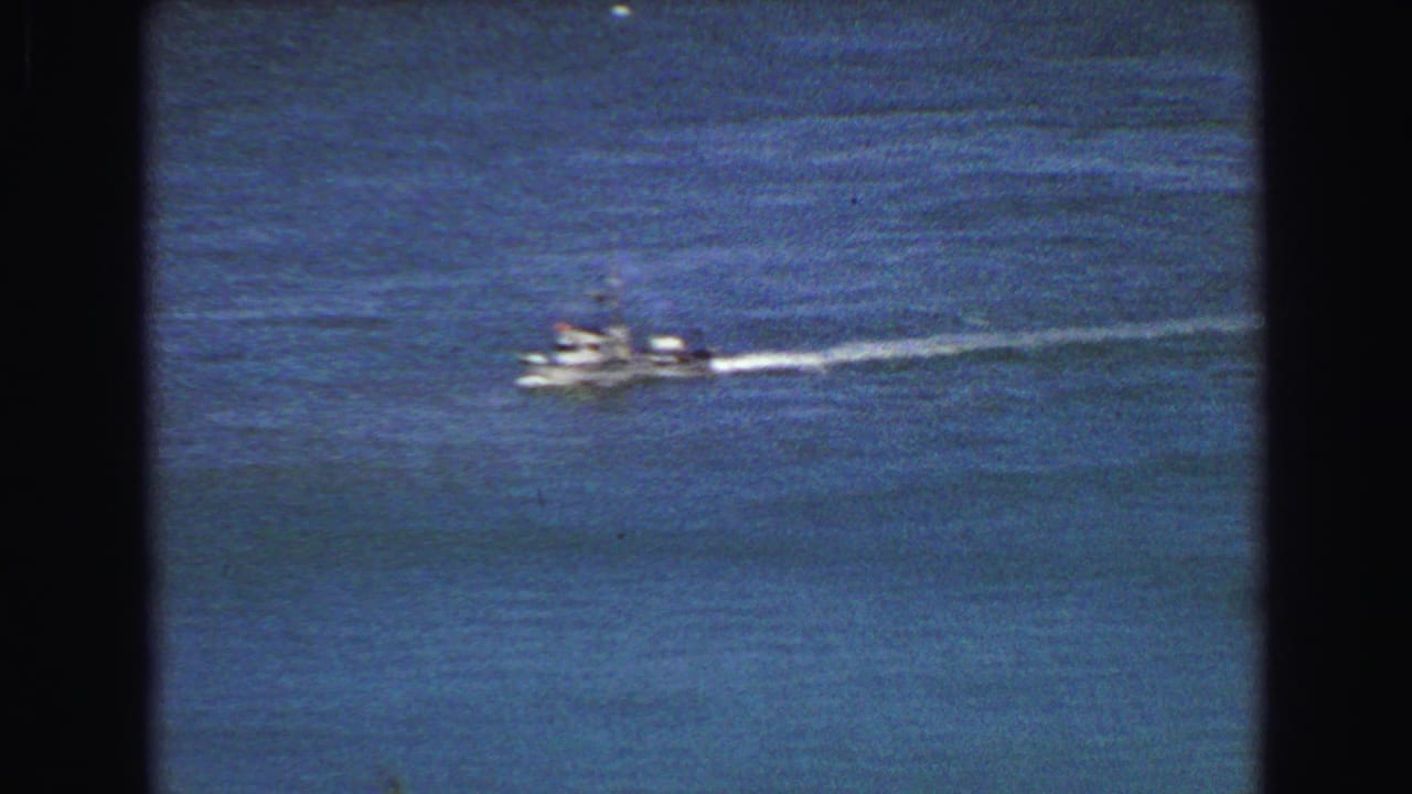 Small boat crossing open blue water in 1968 Vancouver footage, leaving a bright white wake.