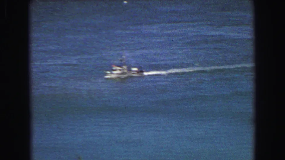 Small boat crossing open blue water in 1968 Vancouver footage, leaving a bright white wake.