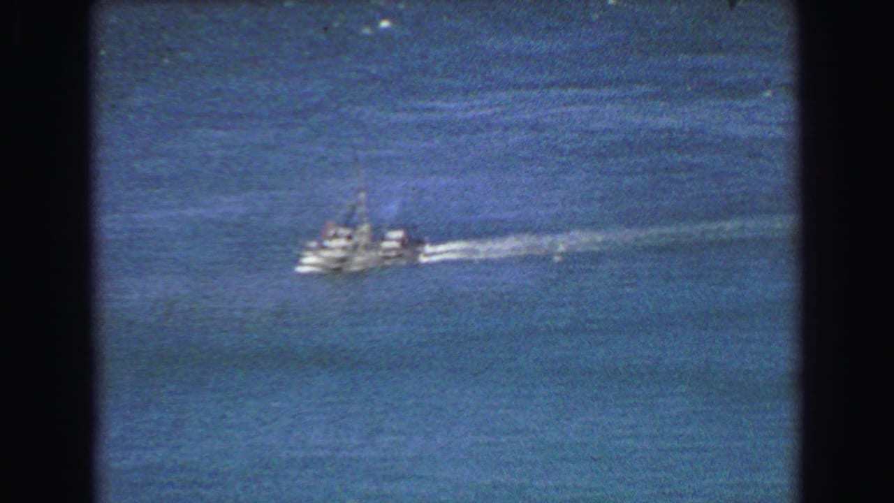 1968 8mm frame showing a white motorboat moving across open water near Vancouver, with grain and dark film borders visible.