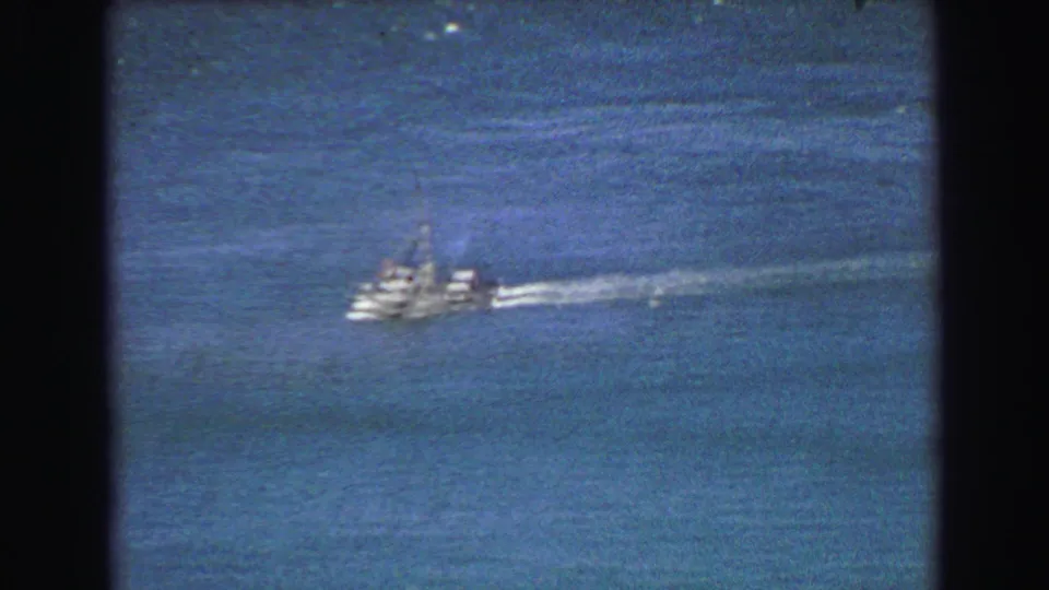 1968 8mm frame showing a white motorboat moving across open water near Vancouver, with grain and dark film borders visible.
