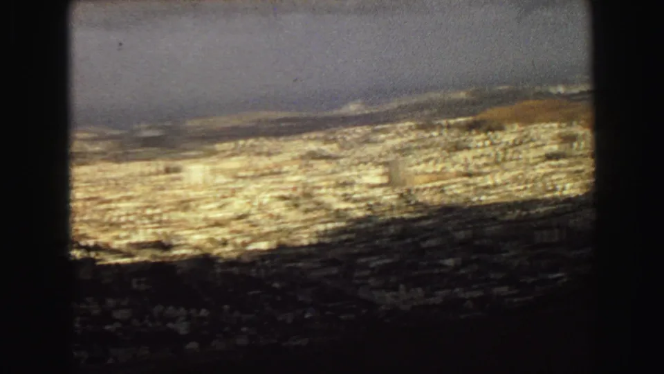 1968 Vancouver home-movie frame showing a hazy elevated panorama over dense urban rooftops toward the coast.