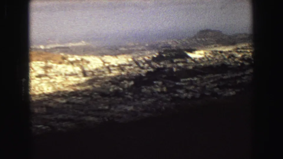 1968 Vancouver panorama frame with dark foreground, clustered buildings, and a low hazy ridge beyond the city.
