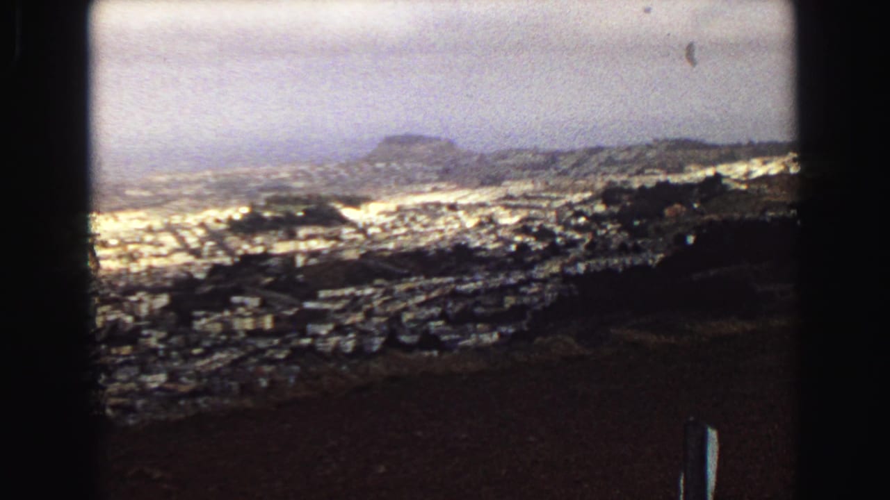 Final 1968 Vancouver frame showing a broad coastal city view with rooftops, hills, and heavy dark foreground framing.