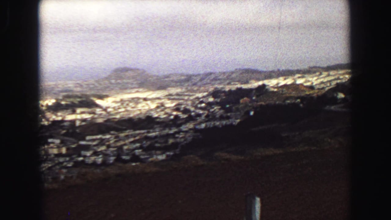 Hilltop view over a brown field toward cemetery markers and distant Vancouver neighborhoods.
