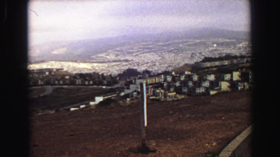 1968 Vancouver hilltop overlook showing a distant city, water, low hills, and roadside posts on 8mm film.