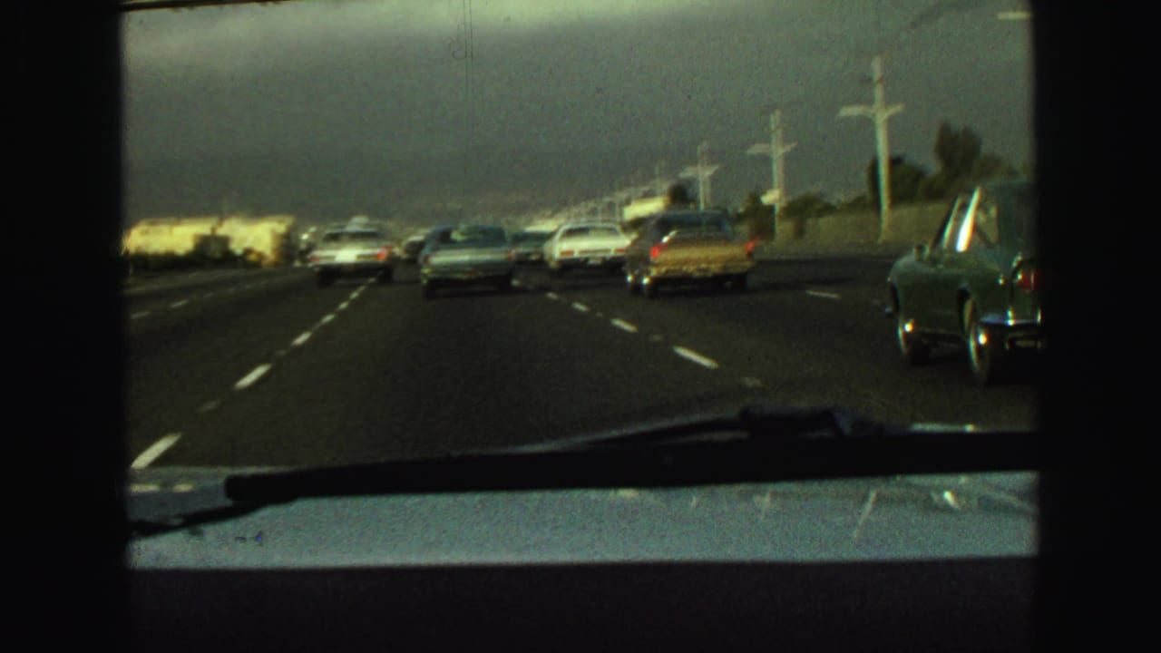 Traffic ahead on a multi-lane highway seen through a car windshield.