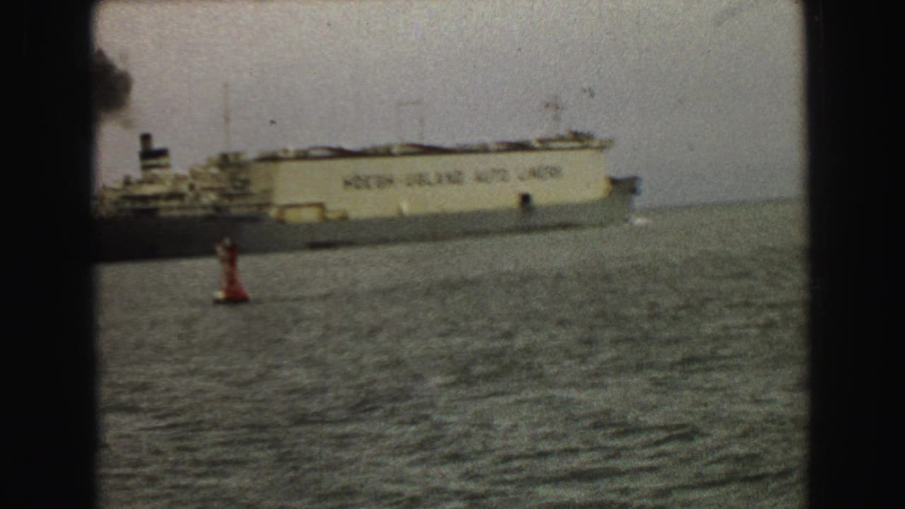 1968 Vancouver harbor view of a tan ocean liner moving across choppy water with a red buoy under a gray sky.