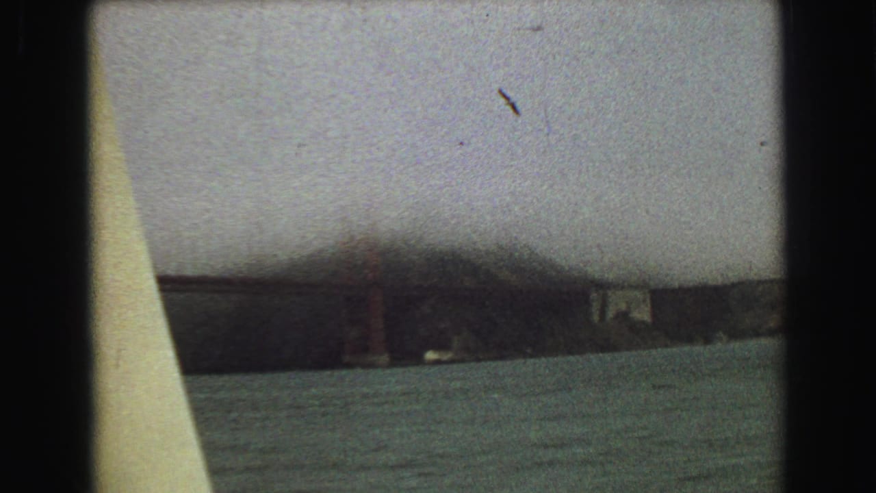 A distant bridge structure appears across Vancouver water in the final 1968 home-movie frame, partly obscured by soft exposure and film grain.