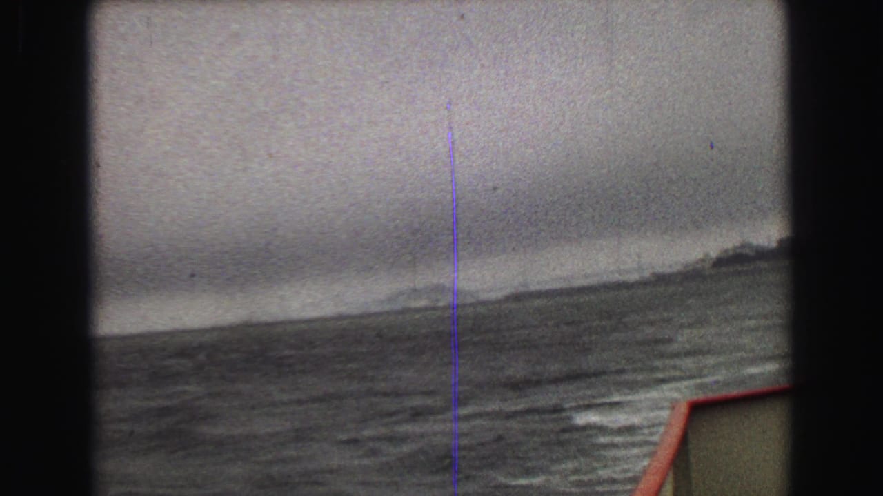 A hazy 1968 Vancouver-area boat view shows rough water, a low shoreline, and a red-edged deck corner.