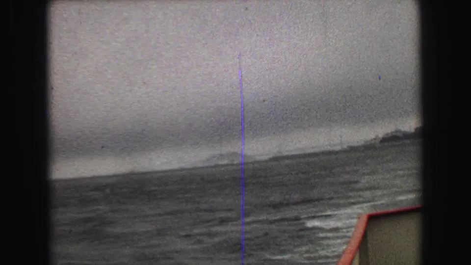 A hazy 1968 Vancouver-area boat view shows rough water, a low shoreline, and a red-edged deck corner.