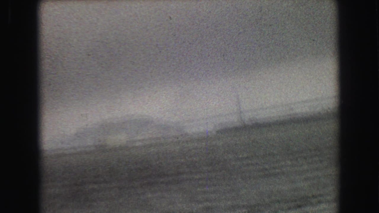 A blurred 1968 Vancouver-area boat view looks toward water, haze, and faint shoreline infrastructure in the distance.