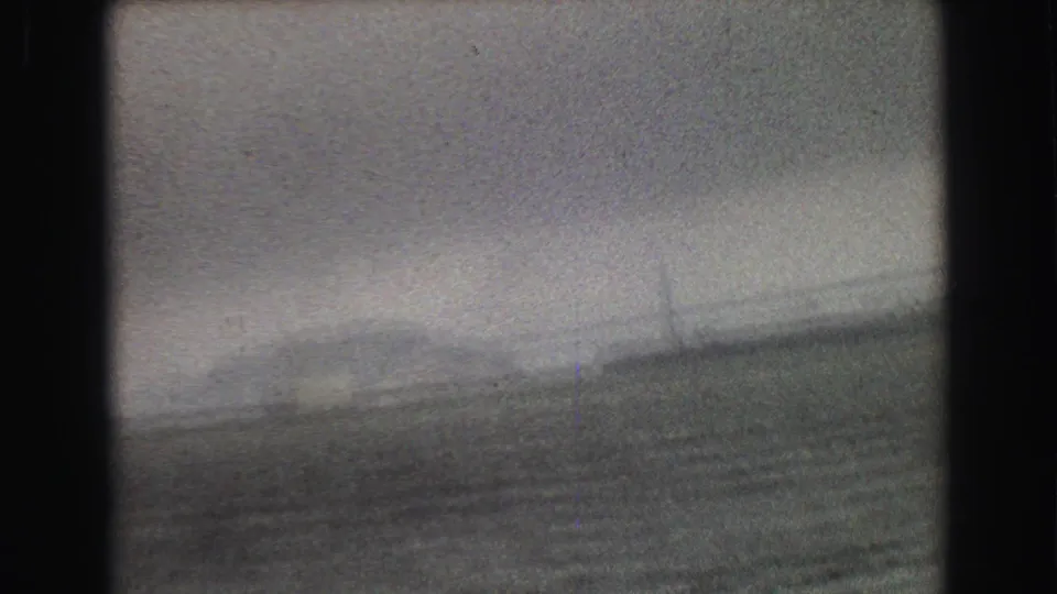 A blurred 1968 Vancouver-area boat view looks toward water, haze, and faint shoreline infrastructure in the distance.