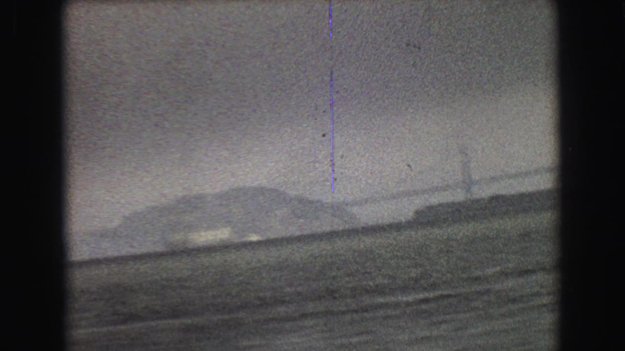 Distant vessel on water seen through soft, grainy 8mm footage.