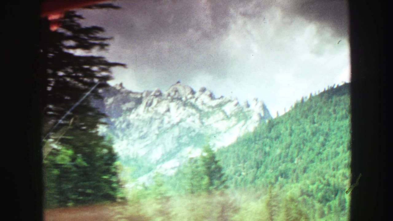 1968 Vancouver-area 8mm view of rocky mountain ridges and dense green forest, likely filmed in motion.