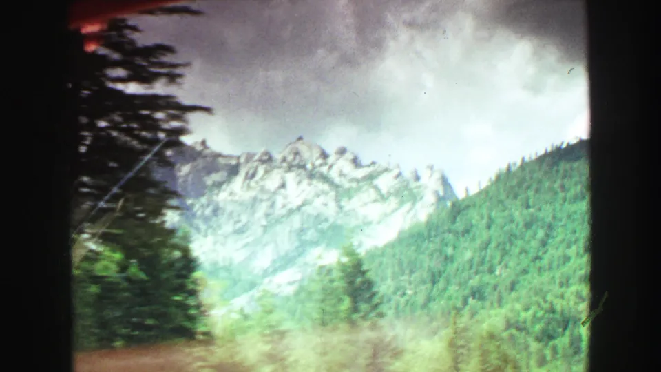 1968 Vancouver-area 8mm view of rocky mountain ridges and dense green forest, likely filmed in motion.