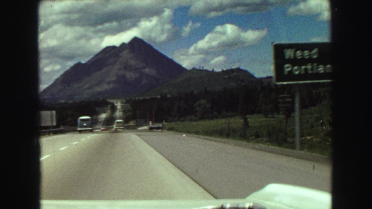 Highway seen from a moving car with a mountain ahead and a Weed Portland sign at right.