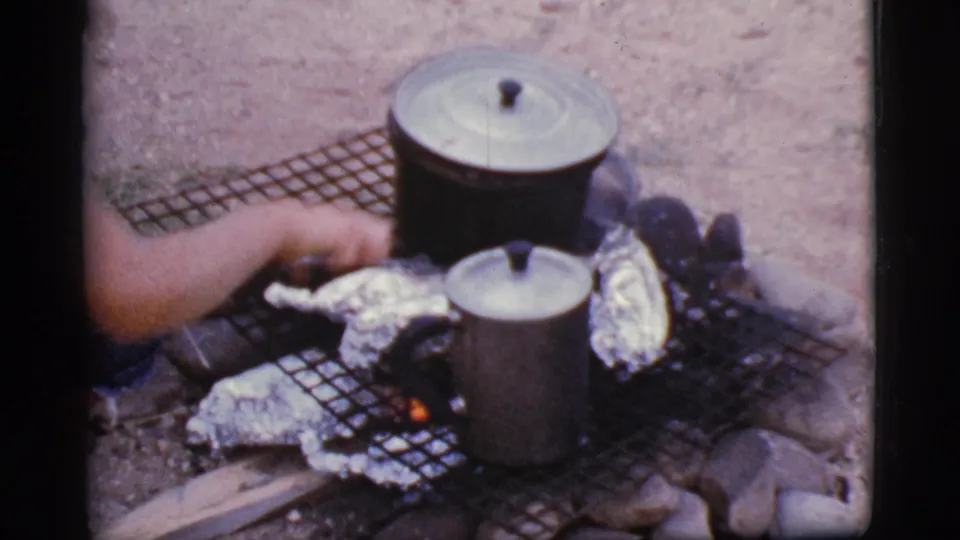 At the end of the clip, a person reaches across the Cottonwood, Arizona fire pit while cookware and foil packets heat over small flames.