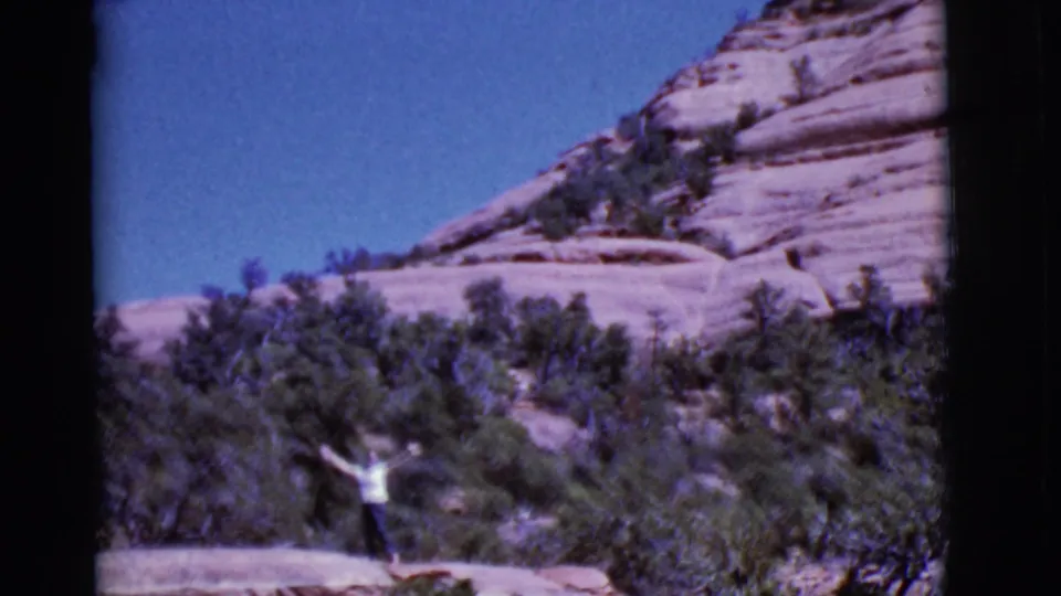 At the end of the 1968 Arizona clip, the woman raises her arms in a wave against red rock and scrub.