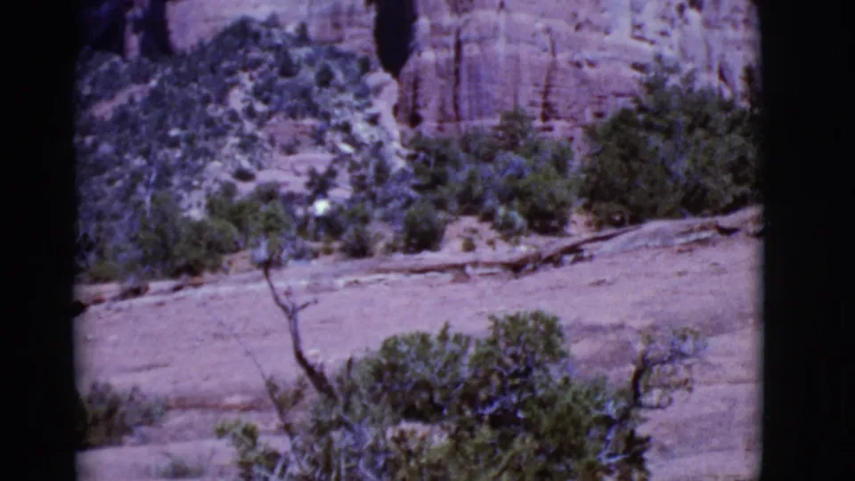 Arizona 1968 8mm view of a distant man in a light shirt crossing scrubby red rock desert terrain.