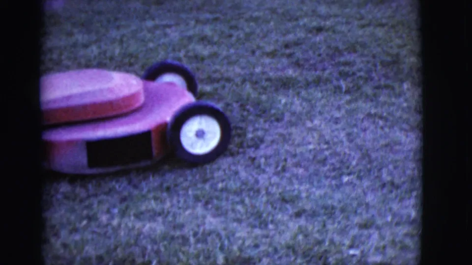 1968 Arizona 8mm frame showing the red push mower in a grassy yard, with soft focus and visible film-frame edges.