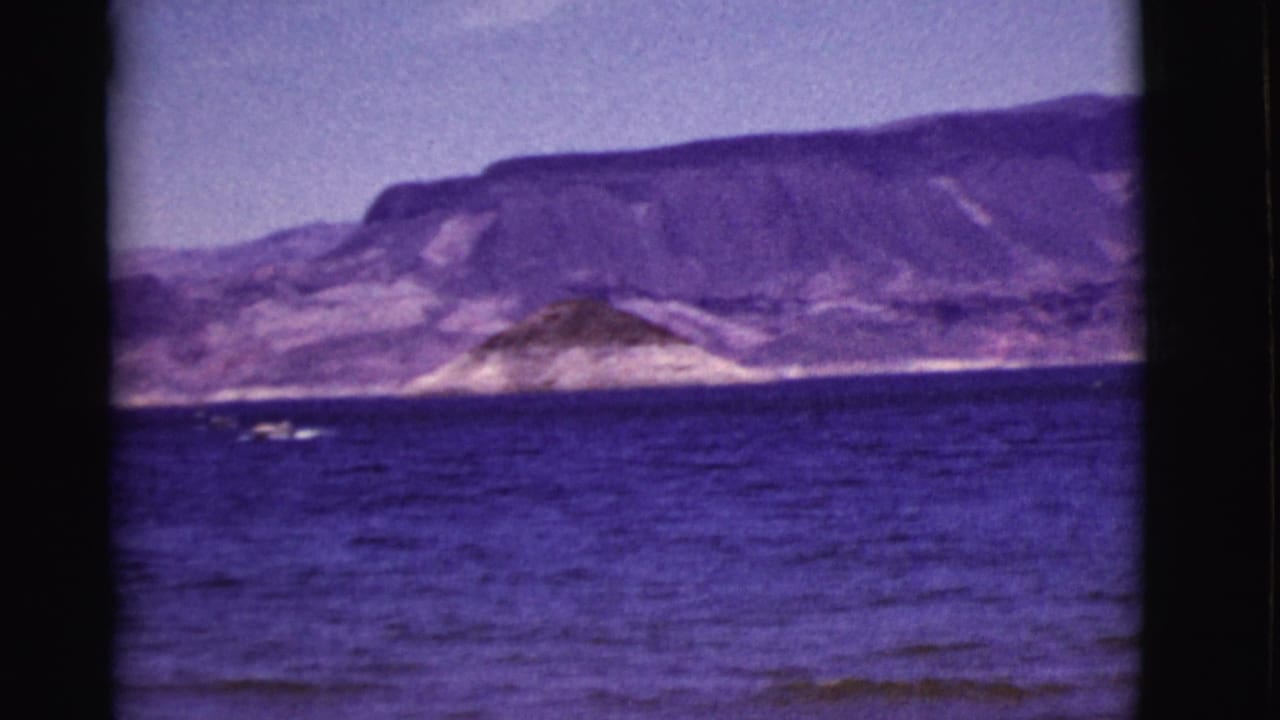 1968 Arizona 8mm view across open water toward low shoreline hills and broad rugged mountains.