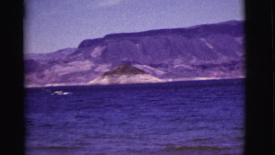 1968 Arizona 8mm view across open water toward low shoreline hills and broad rugged mountains.