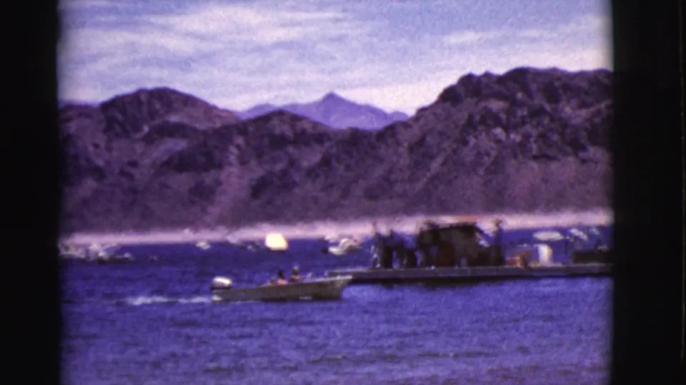Arizona lake scene with nearby boats and a dock-like platform set against rugged mountains in 1968 home-movie footage.