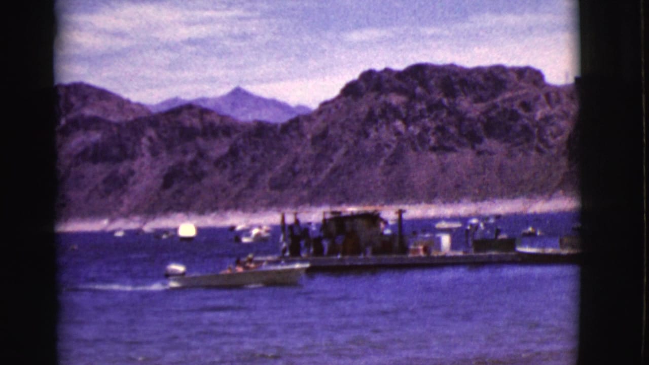 1968 Arizona 8mm frame showing a small motorboat moving near a dock, with people and arid cliffs in the background.