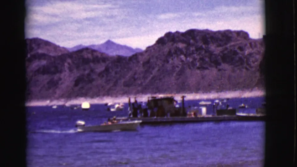 1968 Arizona 8mm frame showing a small motorboat moving near a dock, with people and arid cliffs in the background.