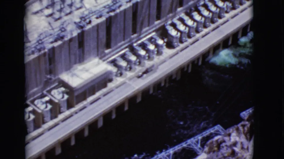 1968 Arizona home-movie frame showing a high-angle view along a building edge, columns, and a dark lower area with foliage nearby.