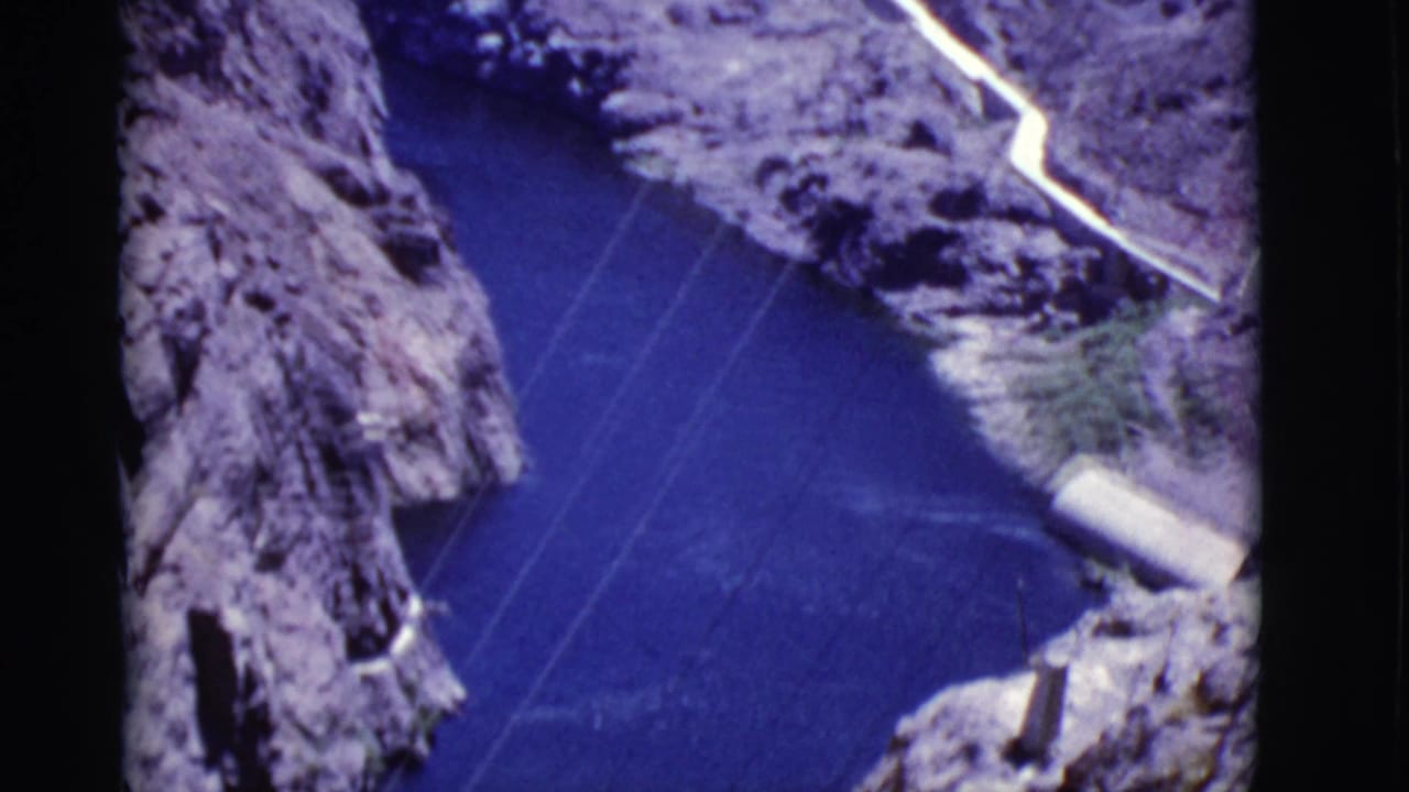 Arizona canyon view with blue river water, steep rock walls, power lines, and a pale route or structure near the canyon edge.