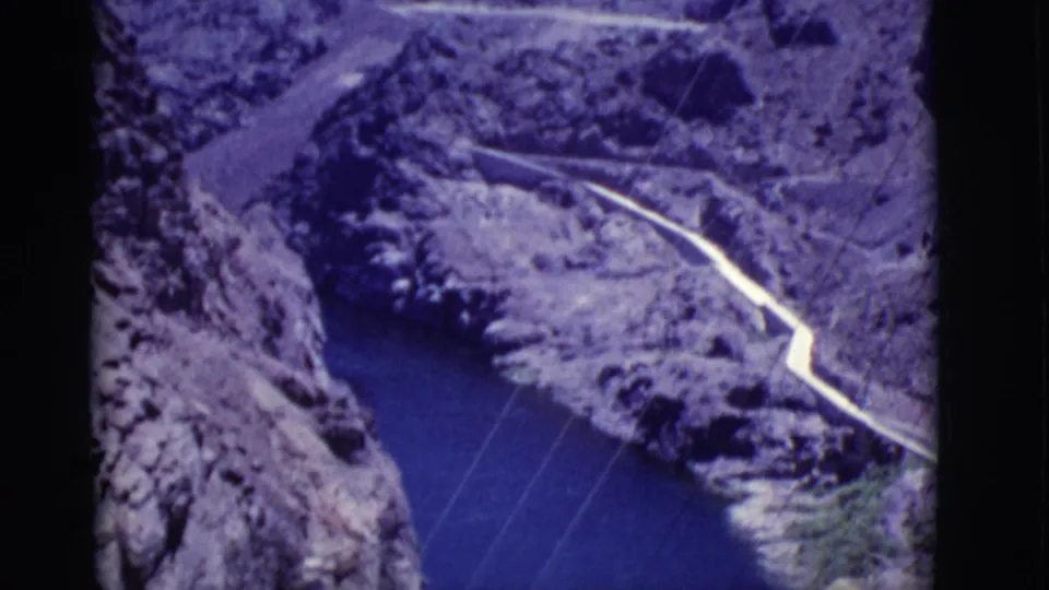 Wider 1968 Arizona canyon perspective showing river water, rocky terrain, power lines, and a winding pale road or project route.
