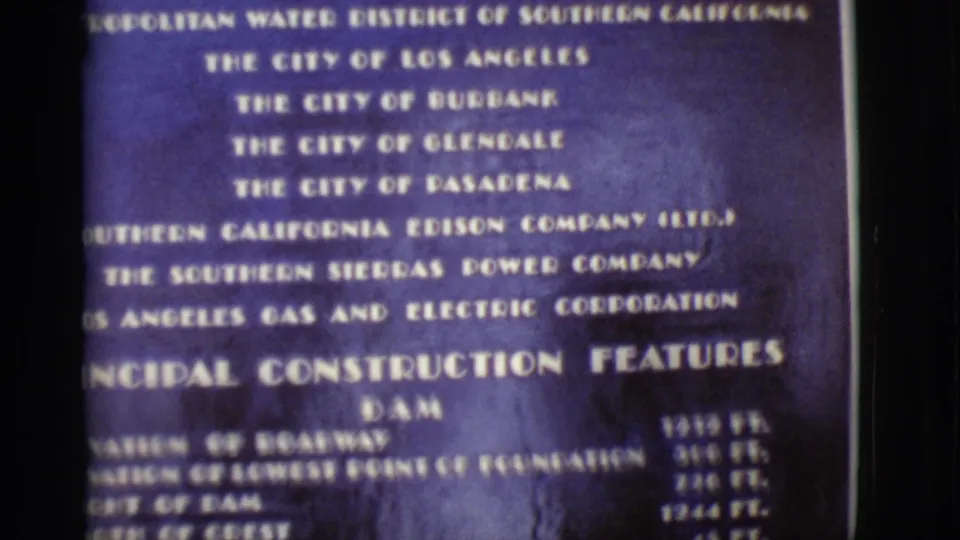 1968 Arizona home-movie frame showing allottee text above a principal construction features heading for the dam.
