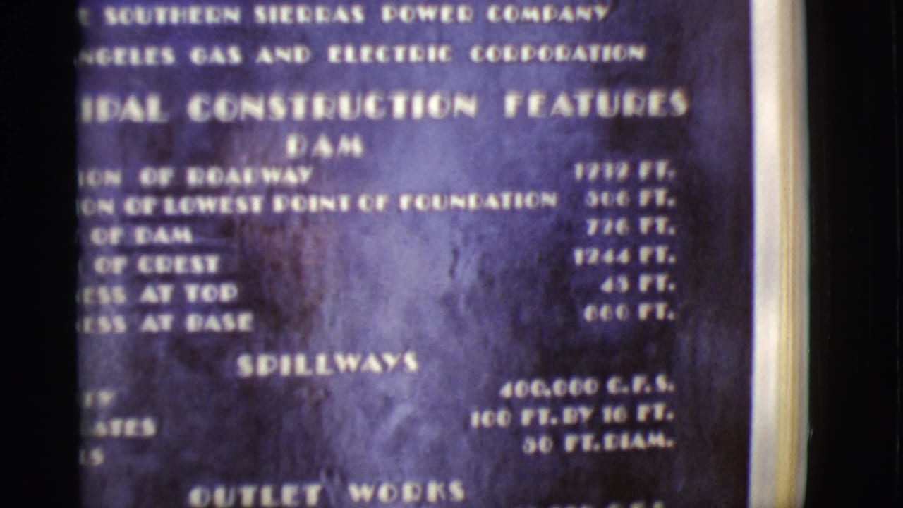 Blue dam construction features board with white text and film frame edges.